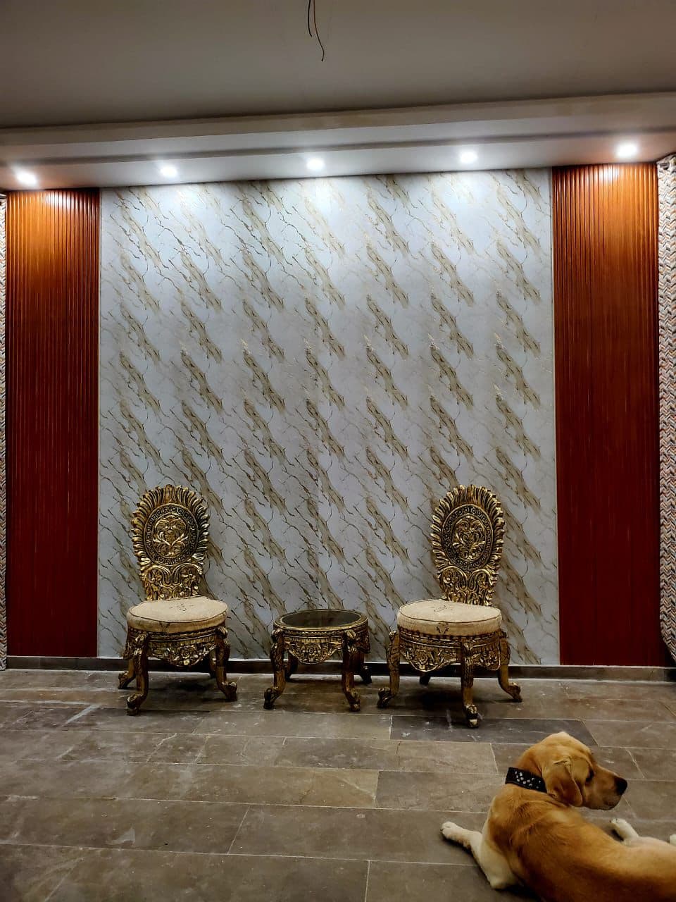 Royal indoor sitting area with carved golden armchairs & marble wall panel